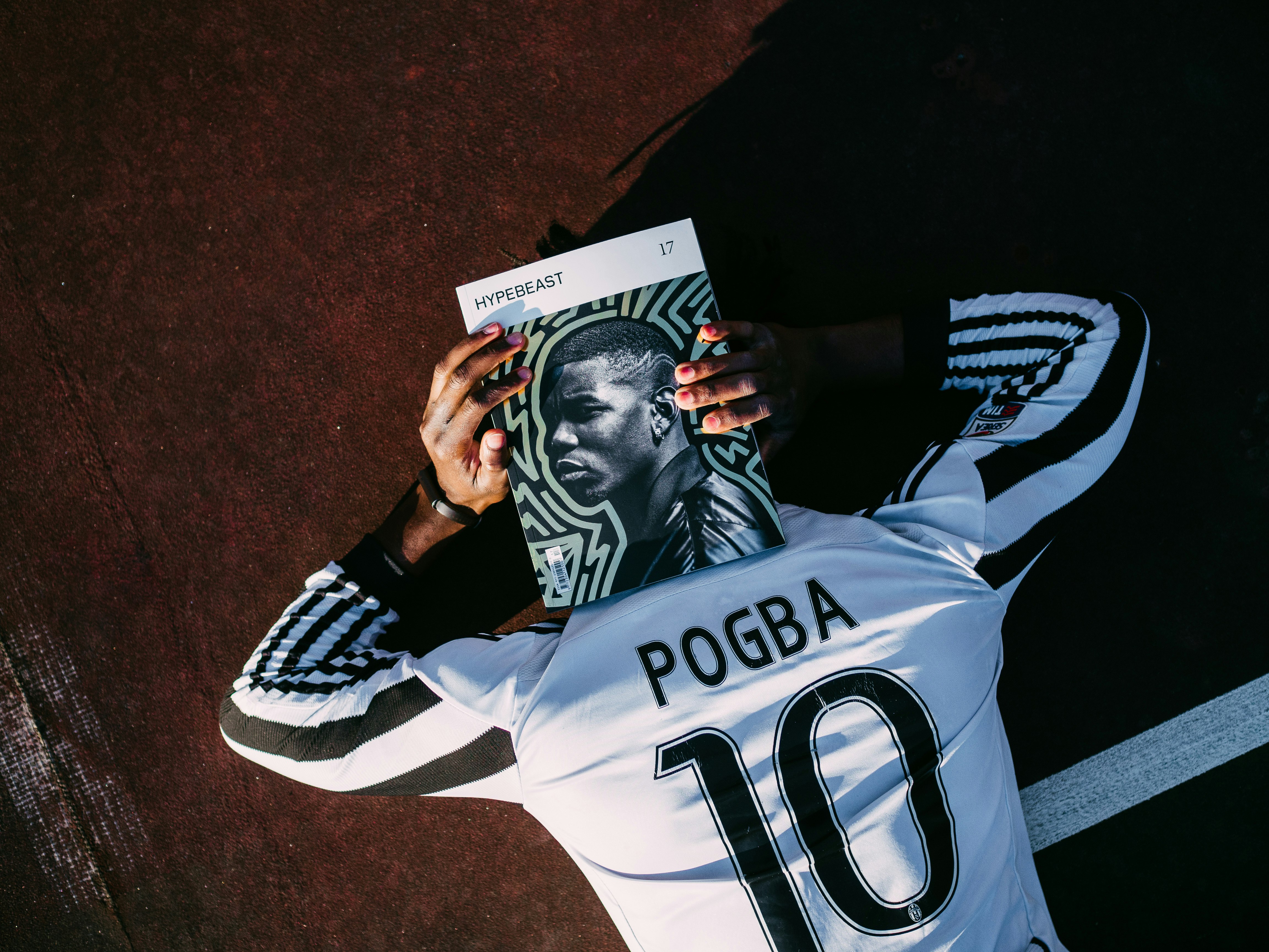 man in white and black adidas jersey shirt holding black and white textile